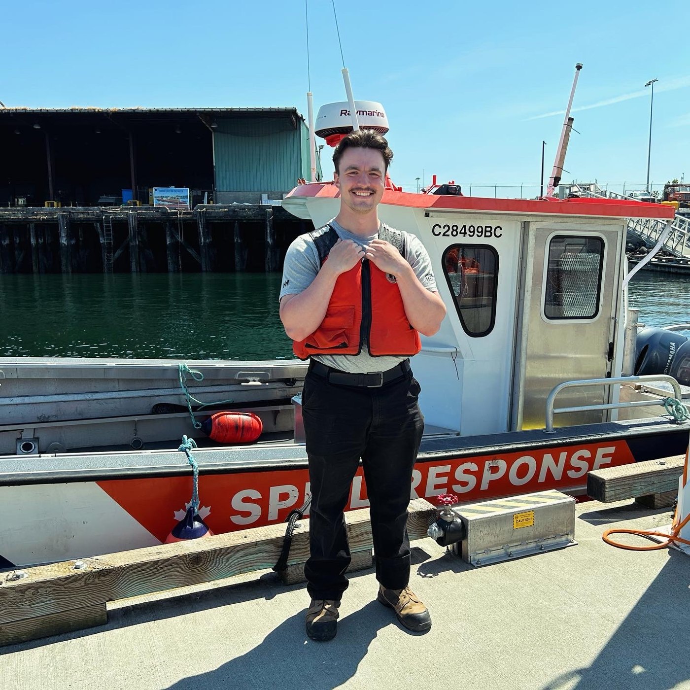 Stuart Davies in a life jacket beside a spill response vessel