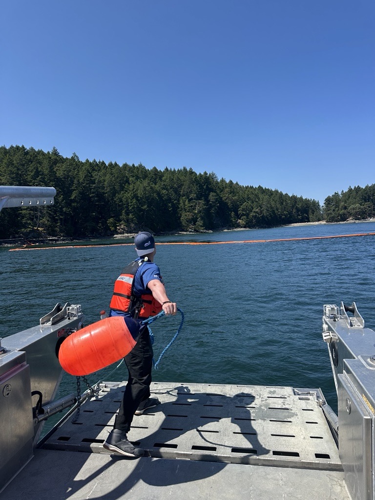 Stuart Davies handling a containment boom buoy on the deck of a spill response vessel